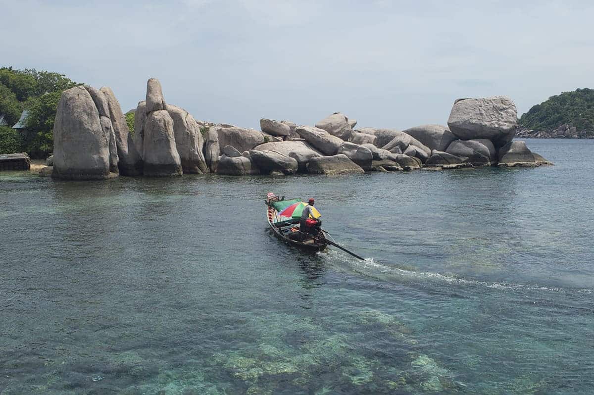 small long tail about on the ocean in front of the island