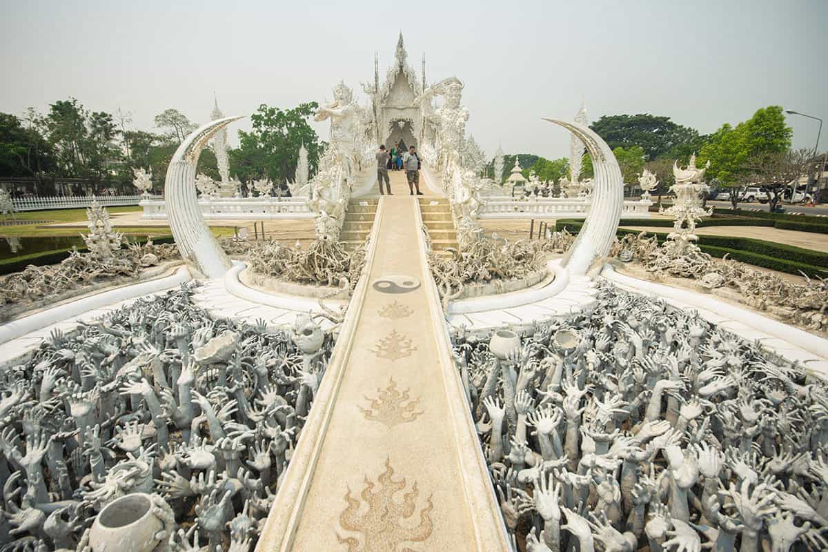 ręce sięgające przez most w białej świątyni w chiang Rai