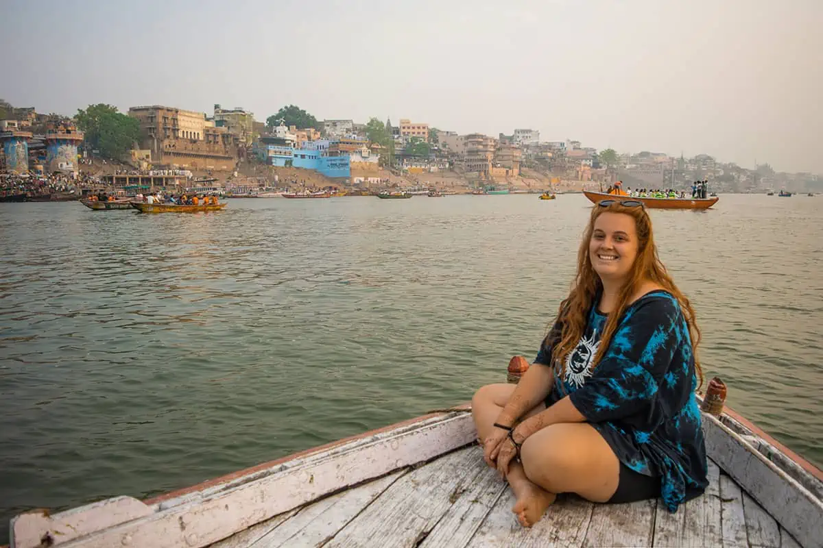 22 Cheapest Countries To Backpack & Travel On A Budget 16 Tasha Amy sitting on a boat on the ganges river in varanasi.