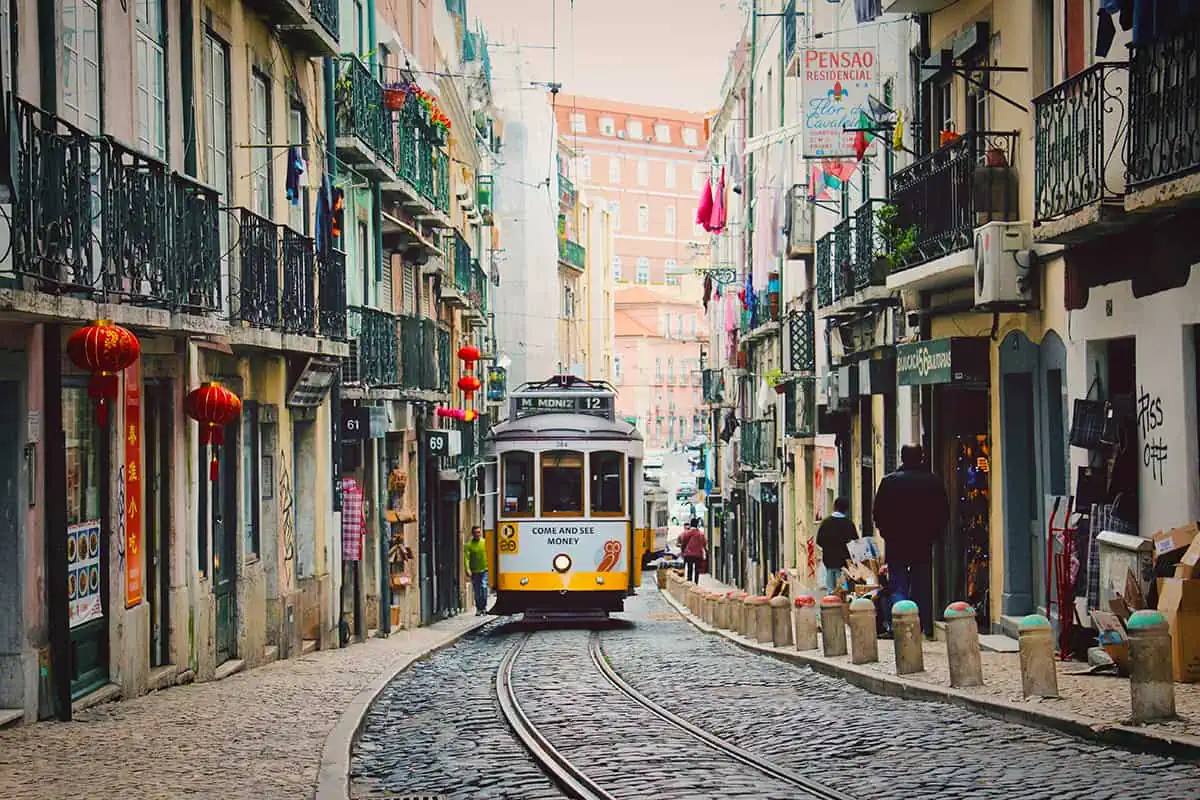 A tram traveling down a narrow street in backpacker-friendly Lisbon.