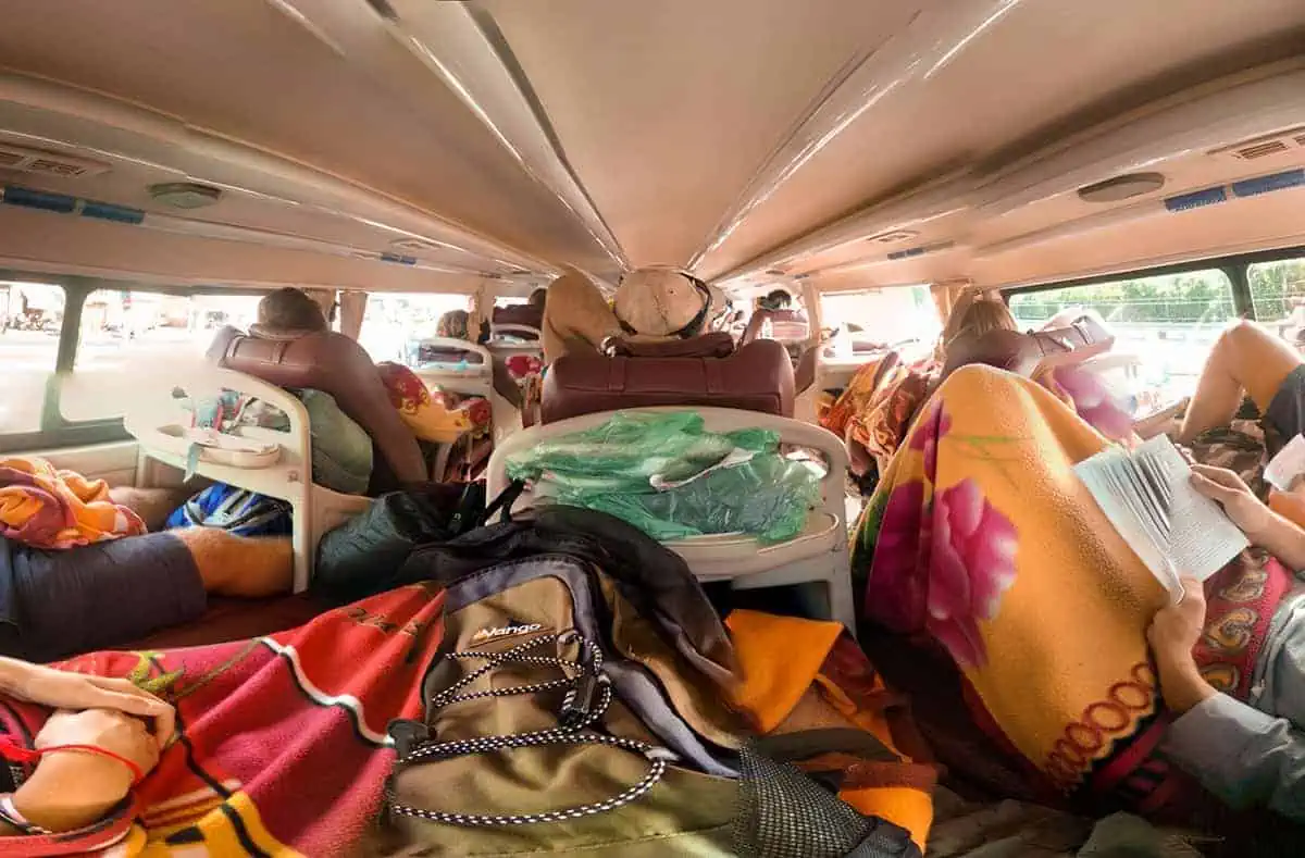 Overcrowded interior of a VIP sleeper bus in Vietnam, with travelers on reclining seats amid a sea of bags, portraying the local bus travel culture.