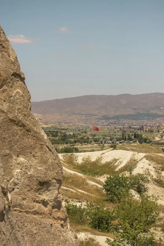 22 Cheapest Countries To Backpack & Travel On A Budget 28 looking out over a dry landscape in cappadocia with a turkey flag on a hill