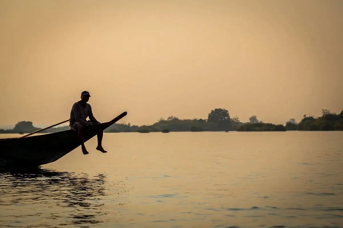 man on boat in don det laos itinerary