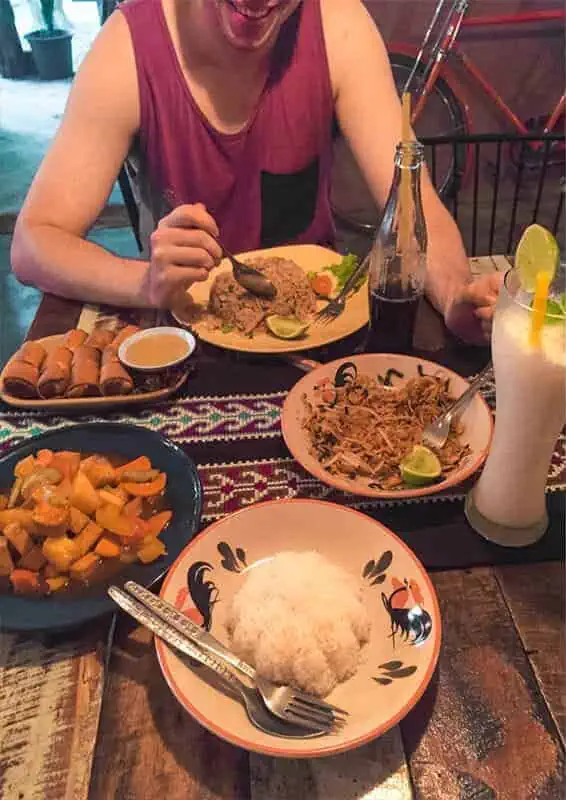 Chiang Mai To Luang Prabang: Slow Boat, Bus Or Flight? 34 a table of spring rolls, fried rice, pad thai, and sweet and sour tofu, as well as drinks from a restaurant in chiang khong
