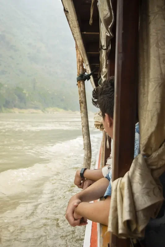 Taking The Slow Boat To Luang Prabang: BEST Tips 2023 7 people hanging out the side of the slow boat in laos