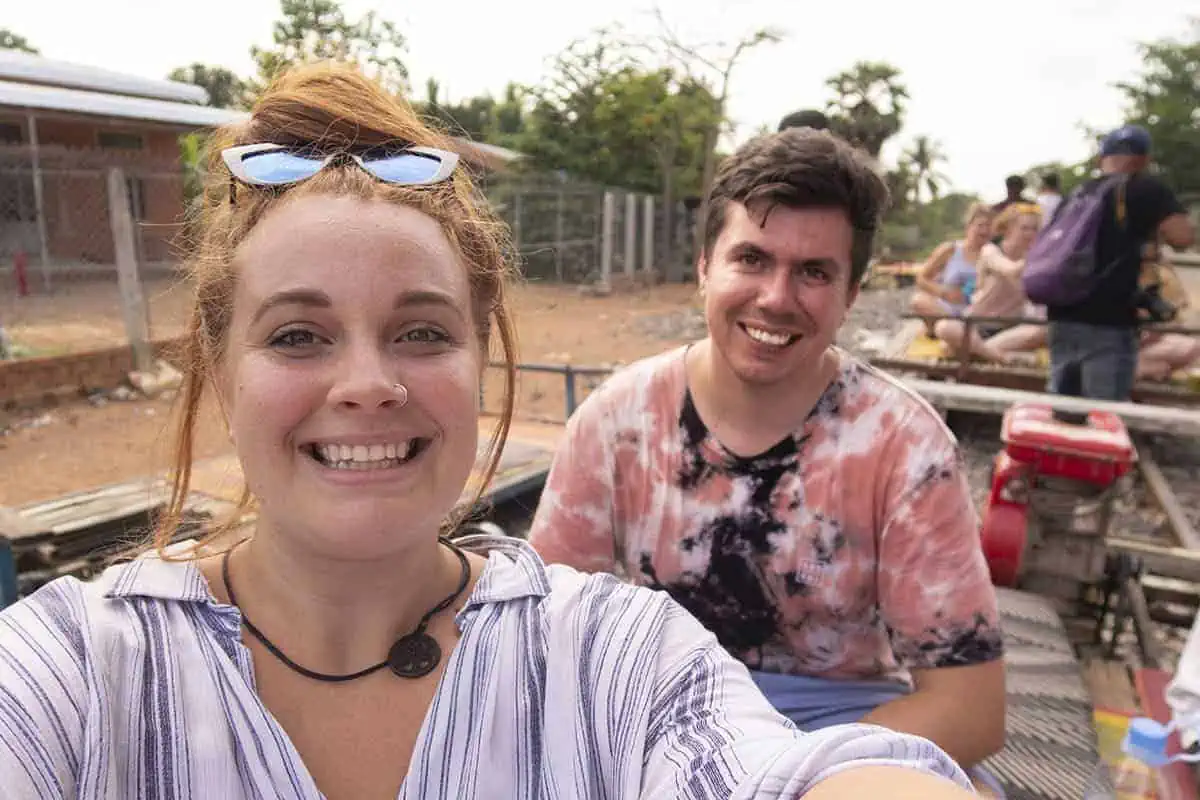 Battambang Bamboo Train: Is It Still Worth Visiting? 2026 55 tasha amy takes a selfie on a bamboo train in Battambang. In the background is some other travelers and a few carts.