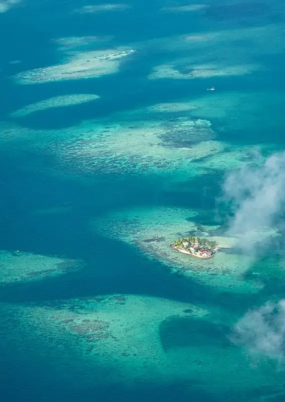 Belize In June: Is Belize Worth Visiting In June? 56 A small, picturesque island surrounded by the azure Caribbean Sea off the coast of Belize, seen from above in the clear weather of June.