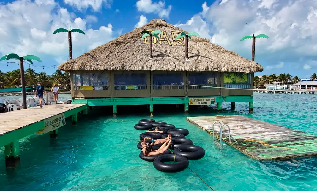 Best Beaches In Ambergris Caye For Swimming & Snorkeling 62 People relaxing on inner tubes in the water at the Palapa Bar and Grill in Ambergris Caye.