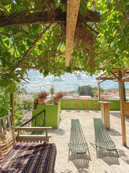 Best Hostels In San Ignacio: 5 Excellent Stays For Travelers On A Budget 61 A sunny rooftop terrace at Bella's Backpackers, displaying comfortable seating and lush greenery, inviting guests to relax and socialize in one of San Ignacio's top hostels.