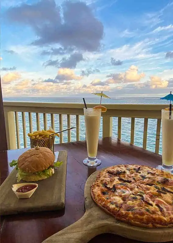 Where To Eat In Rarotonga: BEST Restaurants & Cafes 2026 40 Dining with a view in Rarotonga, featuring a juicy burger, refreshing pina colada, and a mouth-watering pizza, all set against a backdrop of the serene ocean at Captain Andy's Bar and Grill.
