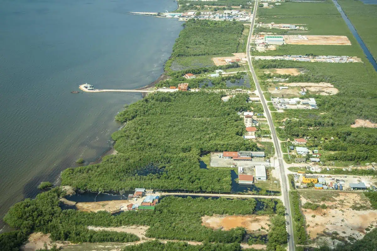 Belize Airport To San Ignacio: BEST Ways To Travel 55 Aerial view of a lush green landscape bisected by a straight road, a scene typical on the flight to Belize airport