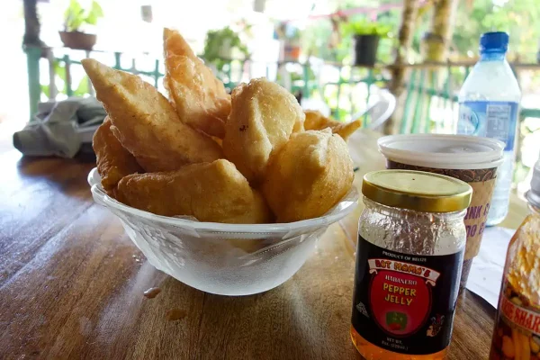 A Belizean breakfast of crispy fry jacks served with a jar of habanero pepper jelly, setting the scene for a traditional morning meal in Belize.