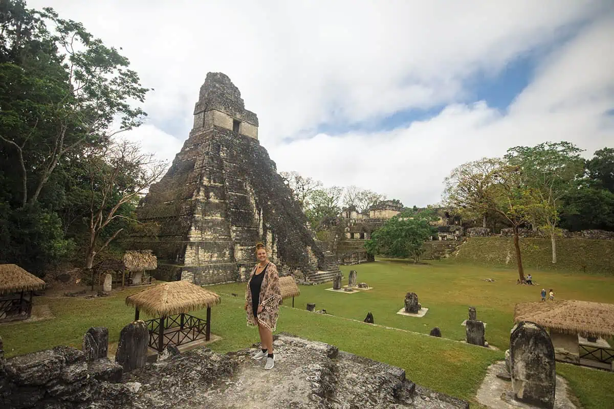 San Ignacio To Tikal & BEST Tikal Tours From San Ignacio 54 Tasha Amy gazing at the iconic Temple I at Tikal National Park, a popular destination for day trips from San Ignacio, with thatched-roof structures dotting the landscape.