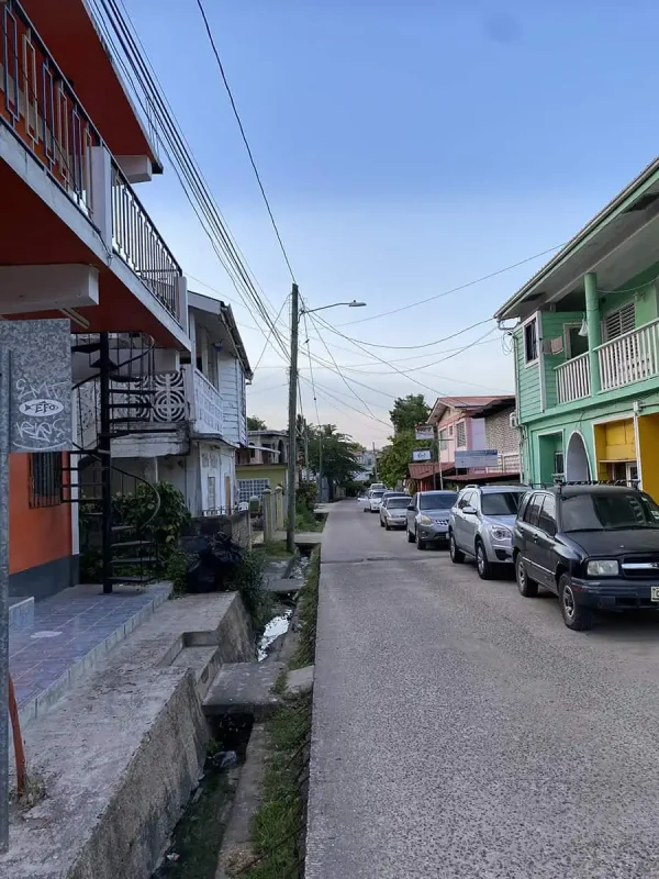Best Things To Do In San Ignacio: Caves, Ruins & Day Trips 55 Another street view in San Ignacio, with pastel-colored buildings and a row of parked cars. The street appears calm and residential, highlighting the town's charm and everyday ambiance