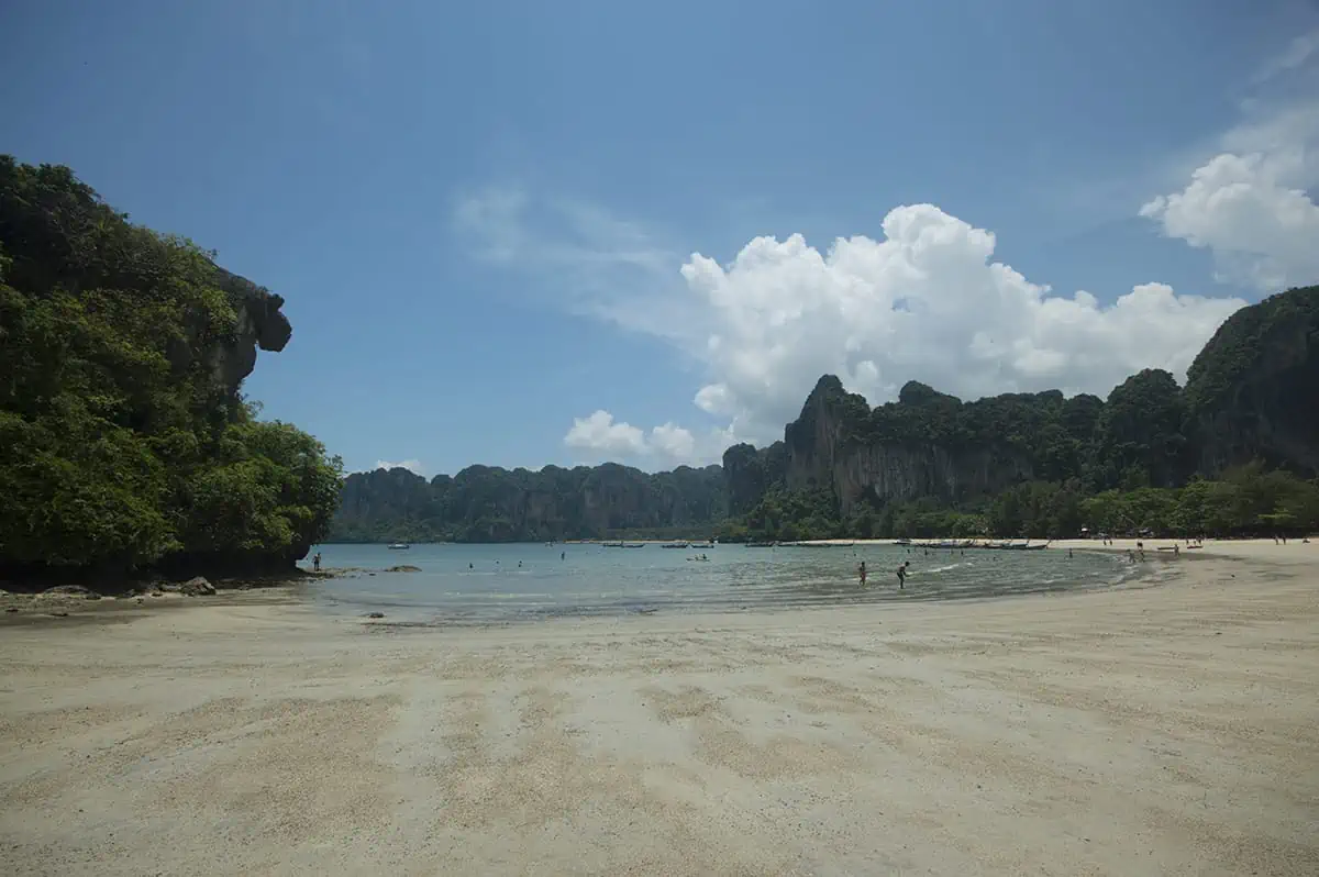 Is Railay Beach Closed: What You Need To Know (2026) 43 A wide view of Railay Beach with its iconic limestone cliffs in the background and a few people enjoying the shallow waters.