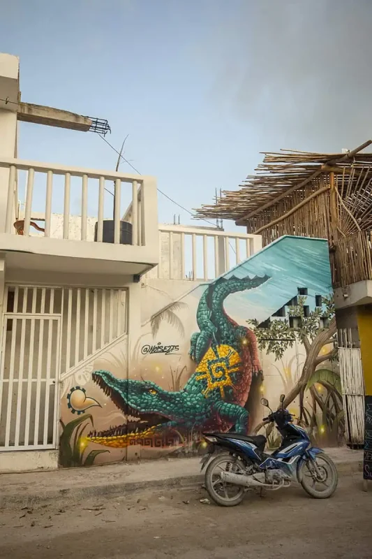Mexico And Belize Itinerary: From 2 to 5 Weeks 56 A vibrant mural on a building wall depicting a green alligator with intricate designs on its back. A motorbike is parked in front of the mural, illustrating the urban art scene in Mexico.