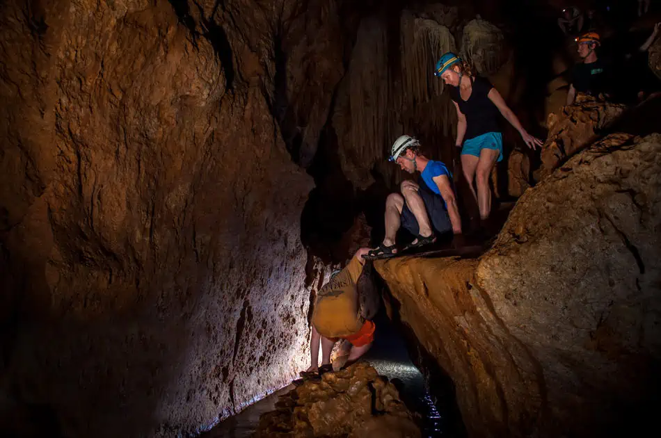 Mexico And Belize Itinerary: From 2 to 5 Weeks 94 Group of adventurous people wearing helmets and headlamps exploring a dark, rocky cave. The rugged terrain and dim lighting emphasize the thrill of cave exploration, showcasing the adventurous side of san ignacio
