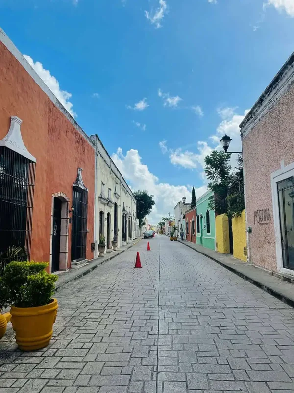 Mexico And Belize Itinerary: From 2 to 5 Weeks 65 Charming street scene in Valladolid, with brightly painted buildings lining a cobblestone road under a clear blue sky. The vibrant facades and quaint atmosphere make it a delightful destination on a Mexico and Belize itinerary