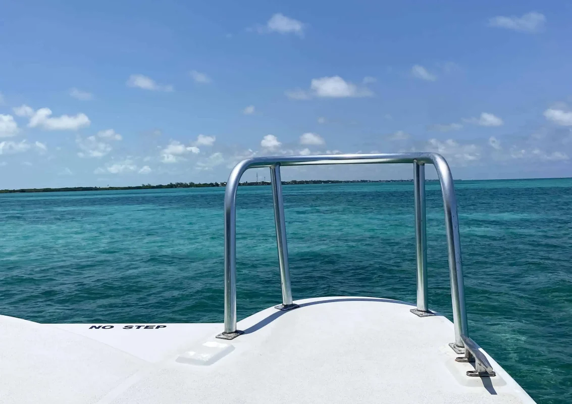 Mexico And Belize Itinerary: From 2 to 5 Weeks 93 The front deck of a boat facing the crystal-clear turquoise waters of the Caribbean Sea under a bright blue sky. The deck has a metal railing, and the water stretches out to the horizon, ideal for crossing the border from mexico the belize