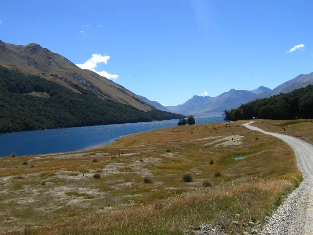 Fiordland & Milford Sound Lord Of The Rings Locations (2026) 20 A winding gravel road curves past Mavora lake toward distant mountains, one of the lord of the rings filming locations in fiordland