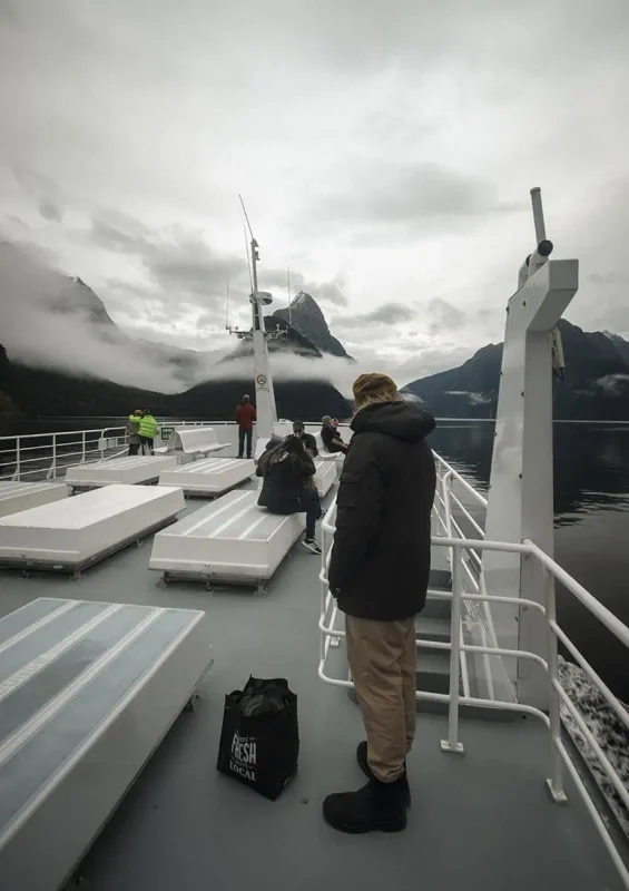 Tourists on the top deck of a Milford Sound cruise boat admiring Mitre Peak.