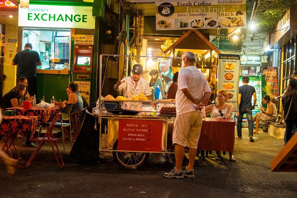 2 Days in Bangkok Itinerary For First-Time Visitors 43 a man in front of a food street stall waiting for food on Khao San Road in Bangkok