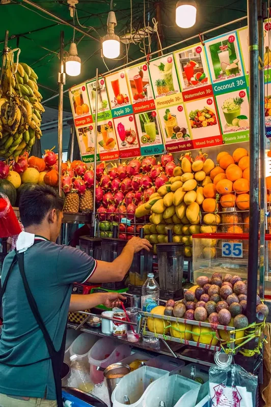 2 Days in Bangkok Itinerary For First-Time Visitors 66 A man making smoothies at his stall in Bangkok with fruit lined up