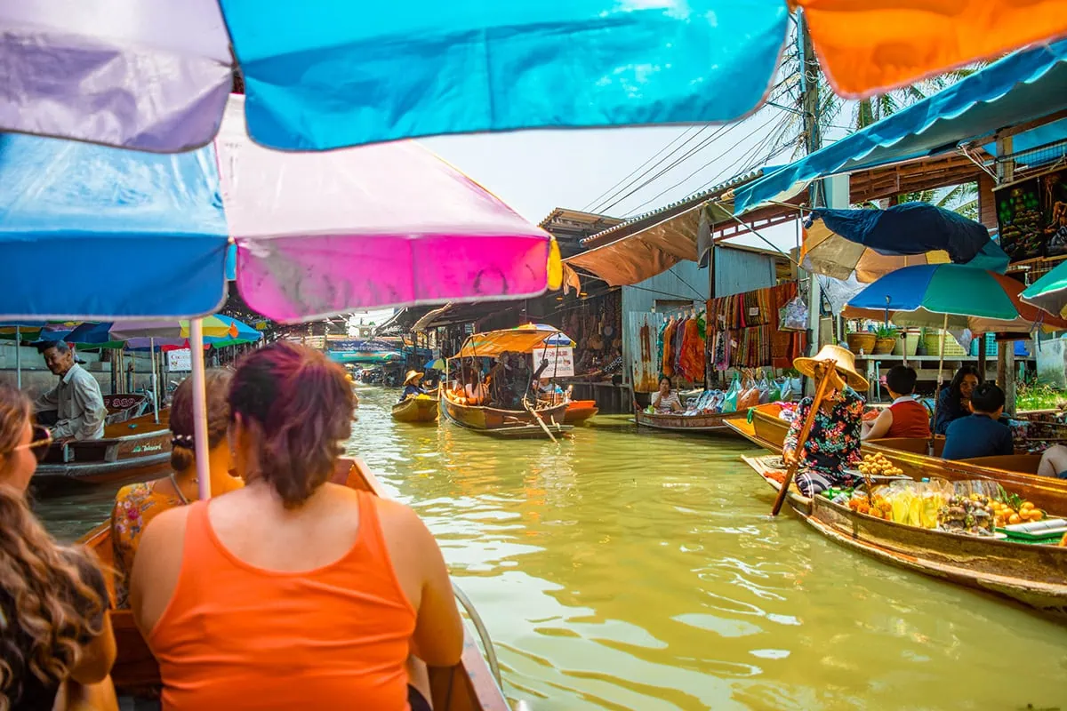 2 Days in Bangkok Itinerary For First-Time Visitors 51 Shaded by a colorful umbrella, floating through the Damnoen Saduak Market with boats nearby selling food