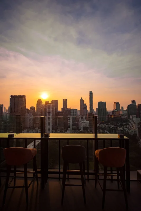 2 Days in Bangkok Itinerary For First-Time Visitors 48 view during sunset from CHAR Sky Bar in Bangkok with bar seats in front