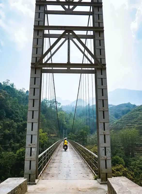 3 Weeks In Vietnam Itinerary: The Perfect First-Time Route 53 Solitary motorcyclist riding across a bridge in the mountains of Sapa
