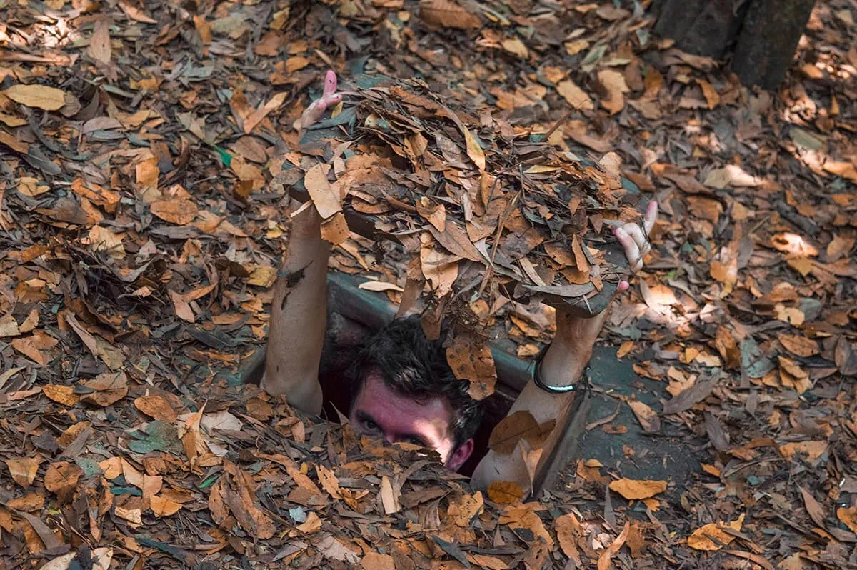 3 Weeks In Vietnam Itinerary: The Perfect First-Time Route 93 Man emerging from a camouflaged tunnel at Cu Chi Tunnels in Ho Chi Minh City