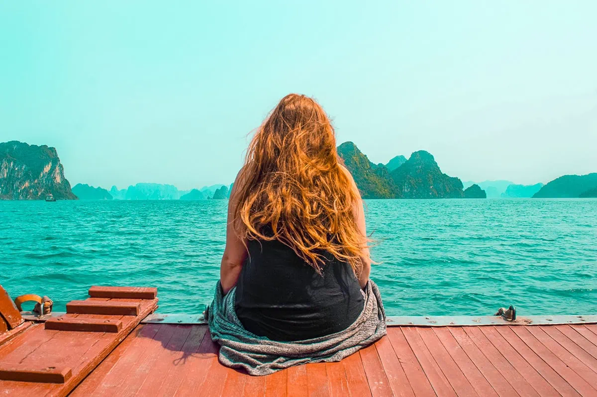 3 Weeks In Vietnam Itinerary: The Perfect First-Time Route 59 Tasha Amy sitting on a boat deck in Ha Long bay looking out to the limestone cliffs emerging from the sea