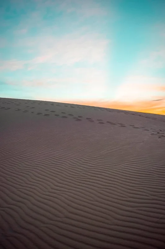 3 Weeks In Vietnam Itinerary: The Perfect First-Time Route 86 the sunrise over the white sand dunes in Mui Ne with footprints in the sand.