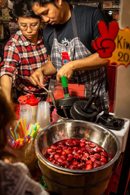 two men preparing strawberry drinks at a stall in the Sunday Night Market in Chiang Mai