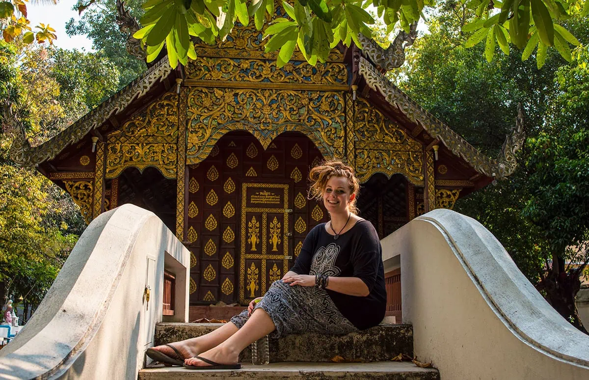 Tasha Amy sitting down on a bridge which leads to a temple in Chiang Mai