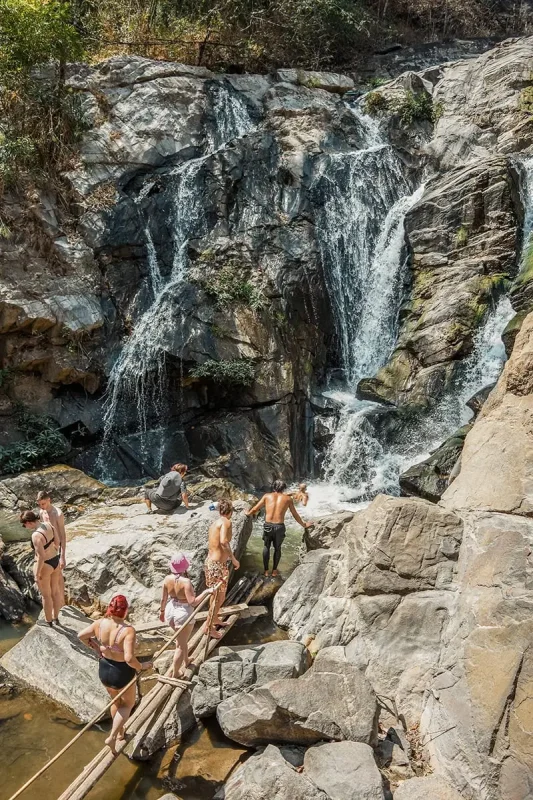 a group of tourists going for a swim under a waterfall on the Pon Elephant Sanctuary tour in Chiang Mai