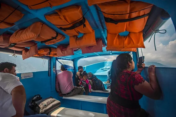 two men, a family, and a local women sitting inside a lancha boat with life jackets hanging from the roof