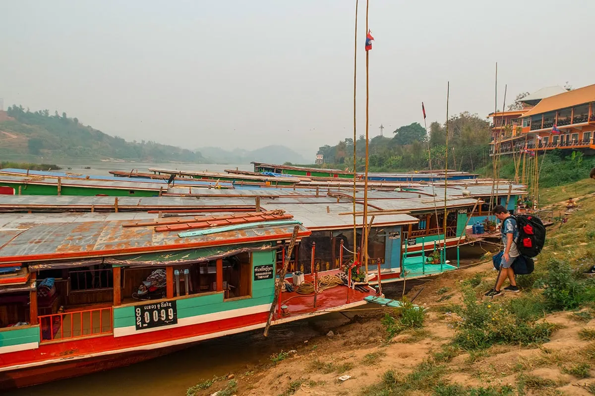 Slow Boat Laos: My Honest Guide After Doing It Twice (2026) 38 A man with a backpack climbing on board the slow boat at Huay Xai