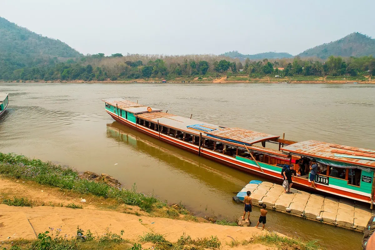 Slow Boat Laos: My Honest Guide After Doing It Twice (2026) 50 Boats moored up at Luang Prabang with passengers disembarking