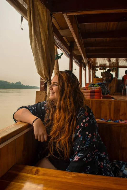 Slow Boat Laos: My Honest Guide After Doing It Twice (2026) 35 Tasha Amy smiling looking out over the Mekong River from the premium slow boat