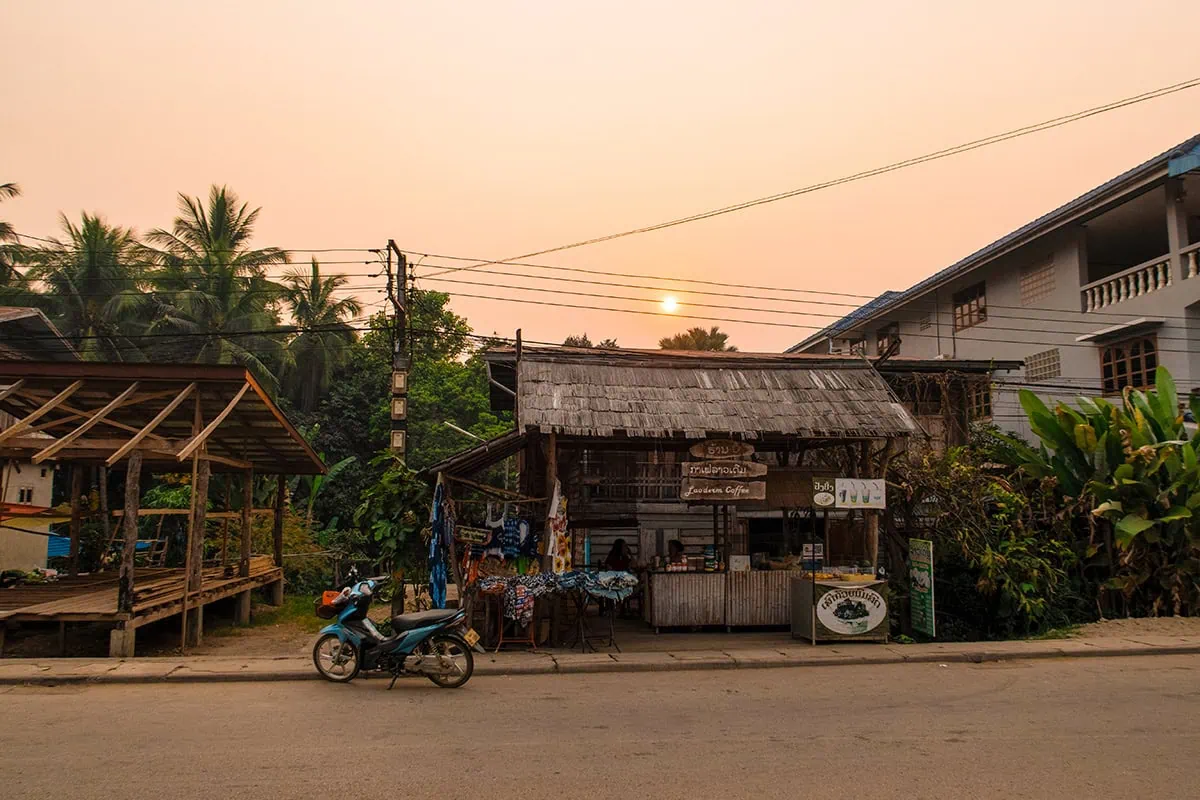 Slow Boat Laos: My Honest Guide After Doing It Twice (2026) 37 Sunset in Huay Xai with a coffee shop and motorbike in the foreground