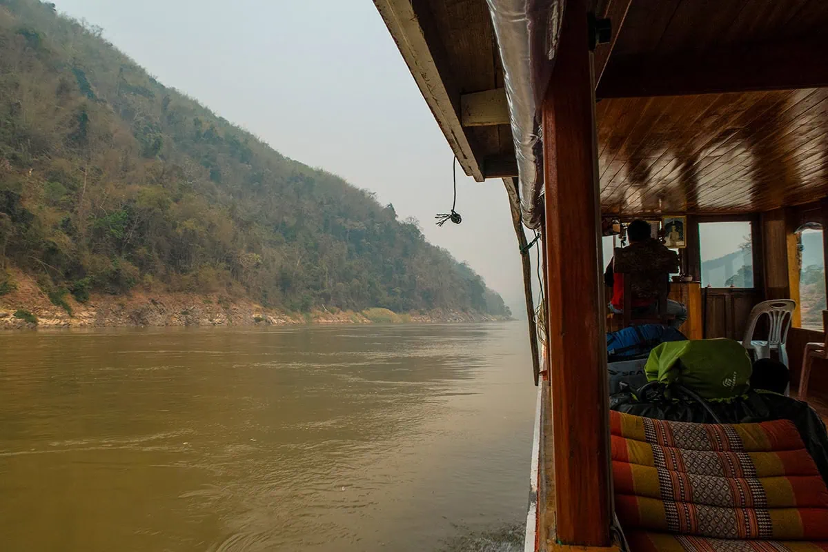 Slow Boat Laos: My Honest Guide After Doing It Twice (2026) 34 Sitting behind the driver of the slow boat looking out over the Mekong River in Laos