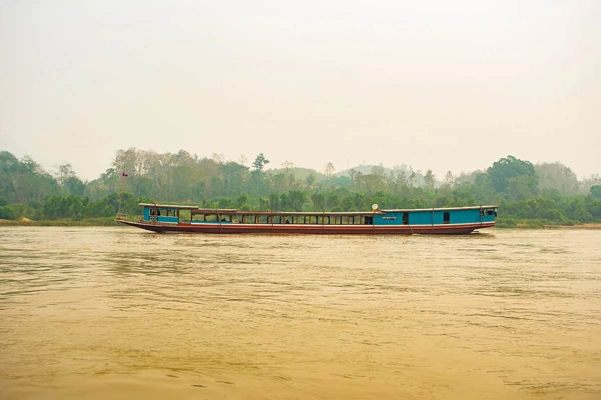 Slow Boat Laos: My Honest Guide After Doing It Twice (2026) 43 A foggy morning on the Mekong River with an empty slow boat in the distance