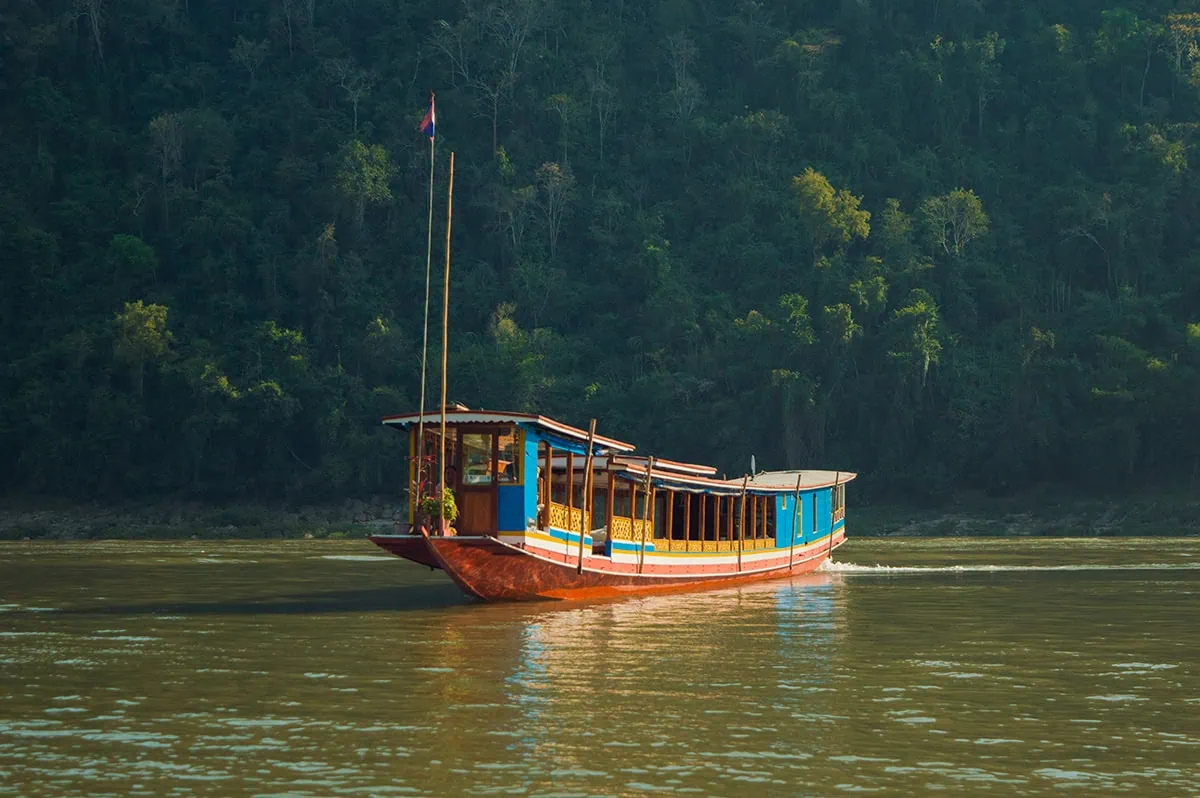 Slow Boat to Laos: What to Expect from Huay Xai to Luang Prabang 4 slow boat to Laos floating on mekong river with jungle behind