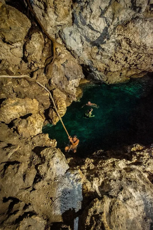 A boy climbing up a rope out of the secret grotto in Lifou.