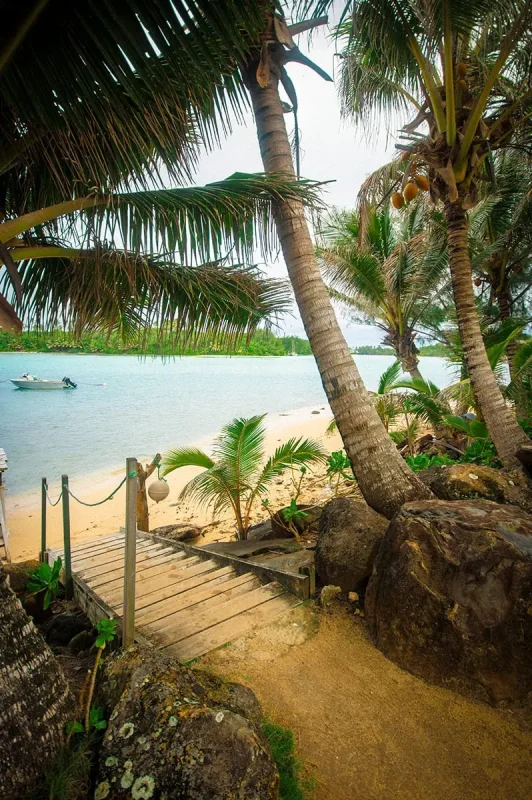 Scooter Hire In Rarotonga: Cost, Requirements, And Tips 23 A pathway and staircase leading down to the beach with a boat floating in the water in Rarotonga
