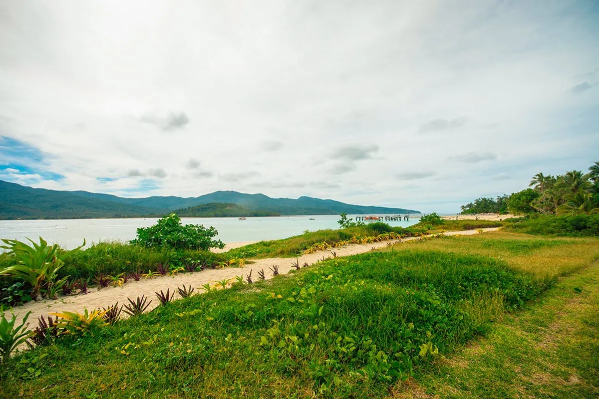 Best Things To Do On Mystery Island, Vanuatu, For Cruise Passengers 10 Looking across a grassy patch and path on Mystery Island toward a wooden pier where the tenders arrive