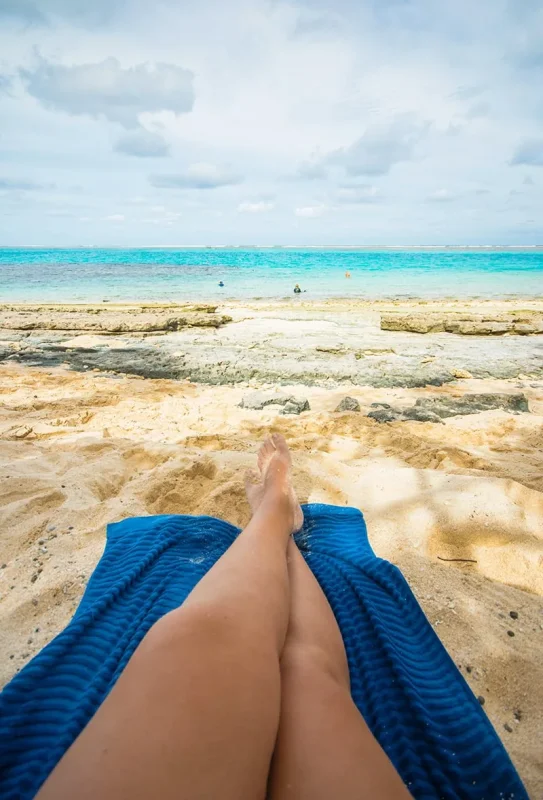 Best Things To Do On Mystery Island, Vanuatu, For Cruise Passengers 12 Close-up of Tasha Amy’s legs resting on a blue towel on the sand of Mystery Island