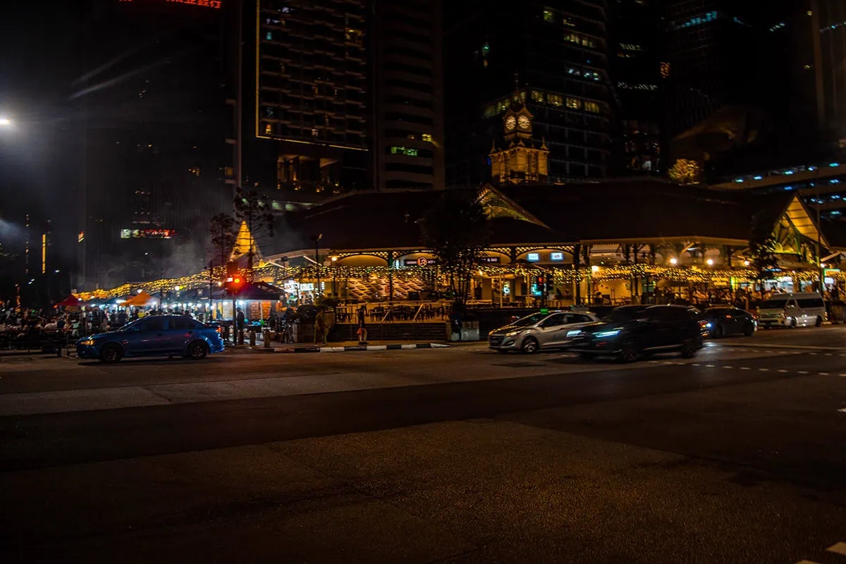 Standing outside of Lau Pa Sat in the evening with cars driving by