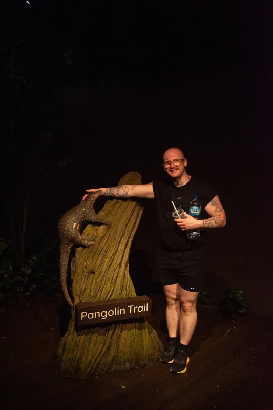 A man standing in front of the Pangolin Trail sign at Night Safari Singapore